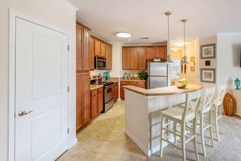 A kitchen with a white island and white chairs.